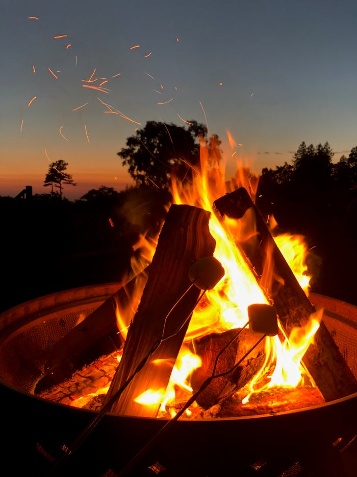 A vibrant campfire with marshmallows toasting at sunset on Mackinac Island.